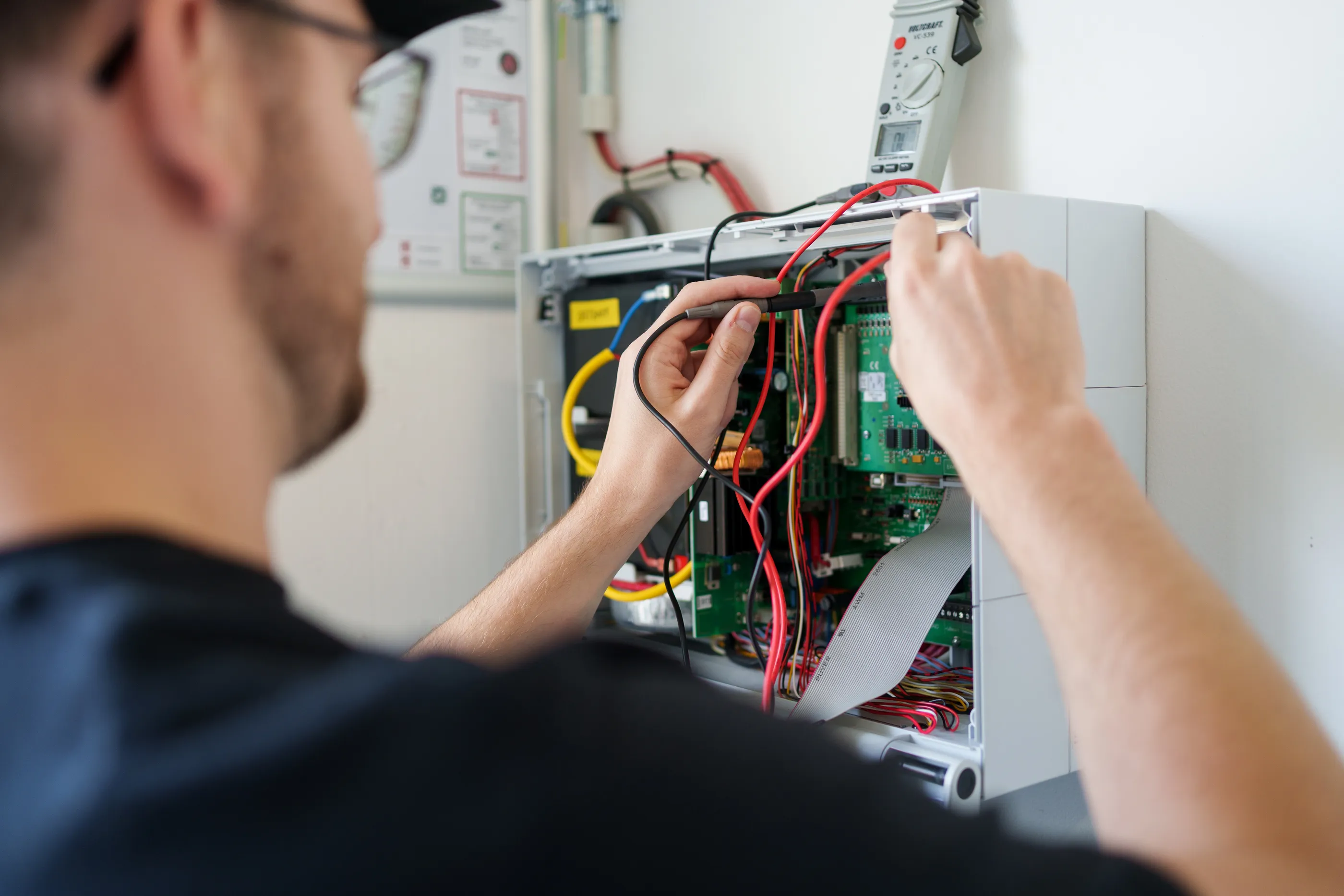 Foto eines Elektrikers an einem Schaltschran, Blick über seine linke Schulter